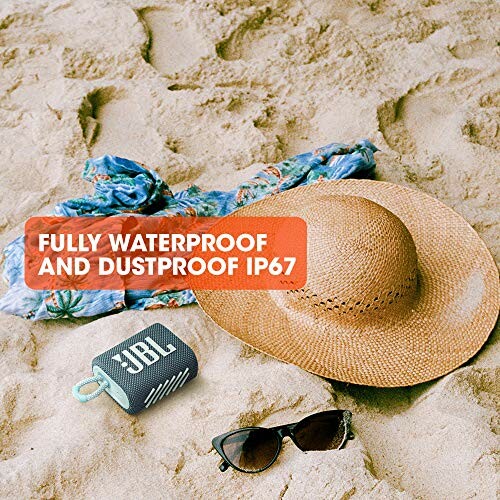 Beach scene with hat, sunglasses, and waterproof JBL speaker.