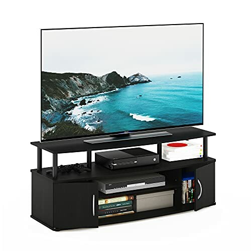 Modern TV stand with a flat-screen TV displaying a coastal image, gaming consoles, books, and DVDs.