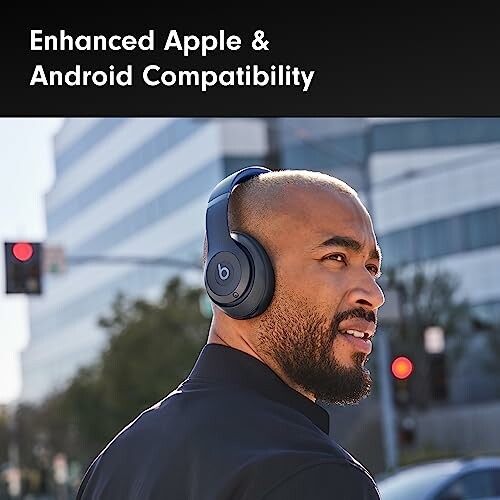 Man wearing wireless headphones outdoors with city buildings in background